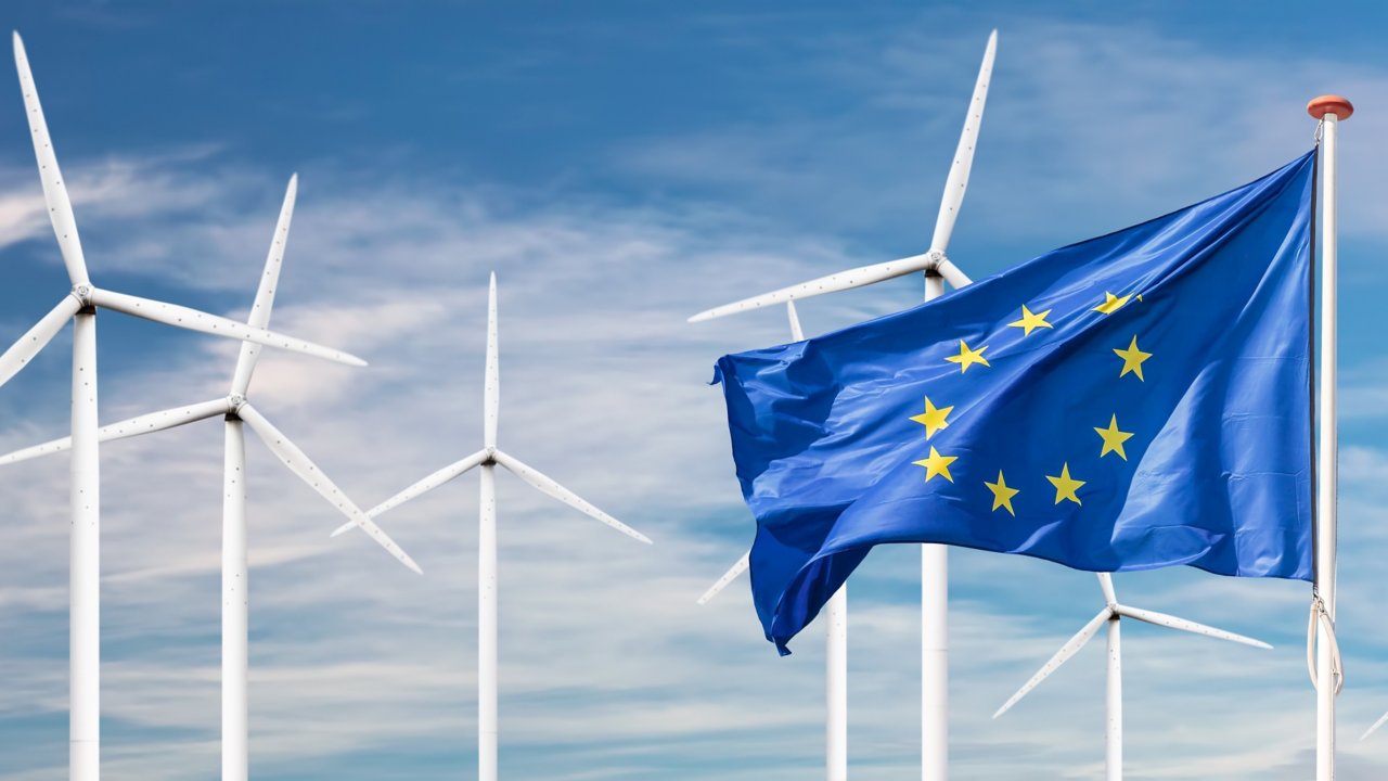 The European Union Flag with white wind turbines in the background