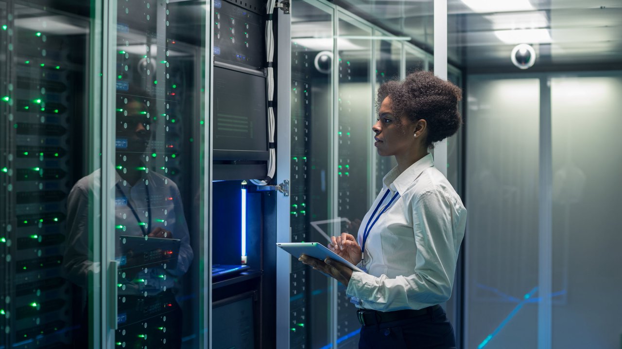 woman holding tablet in front of industrial data centers