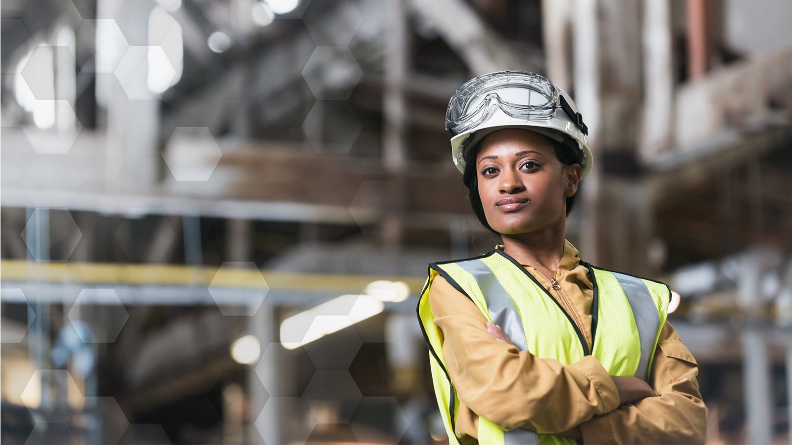 Women wearing hardhat with safety glasses and safety vest in manufacturing facility with lockout/tagout procedures