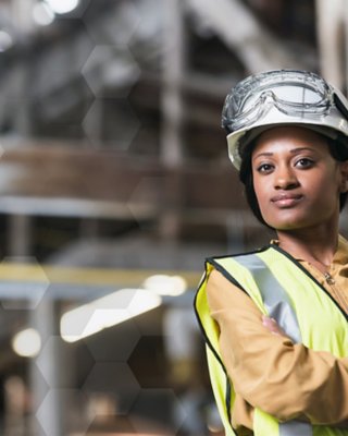 制造工厂中根据上锁挂牌规程佩戴安全帽（带护目镜）并穿戴安全背心的女士