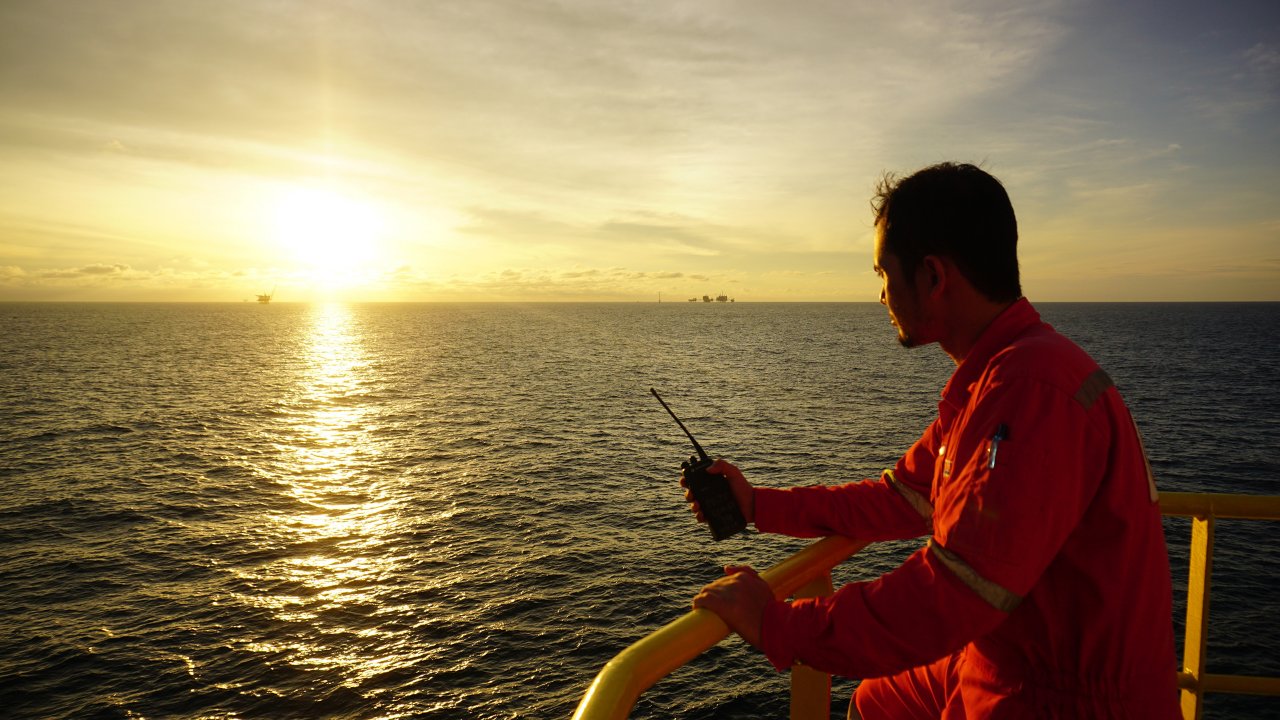 Offshore worker communicate with offshore vessel captain using walkie talkie. Beautiful sunset scenes in the background. 