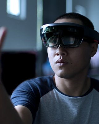 Young Asian student trying mixed reality with VR glasses in the laboratory. Gesture of a man when using Virtual Reality headset.