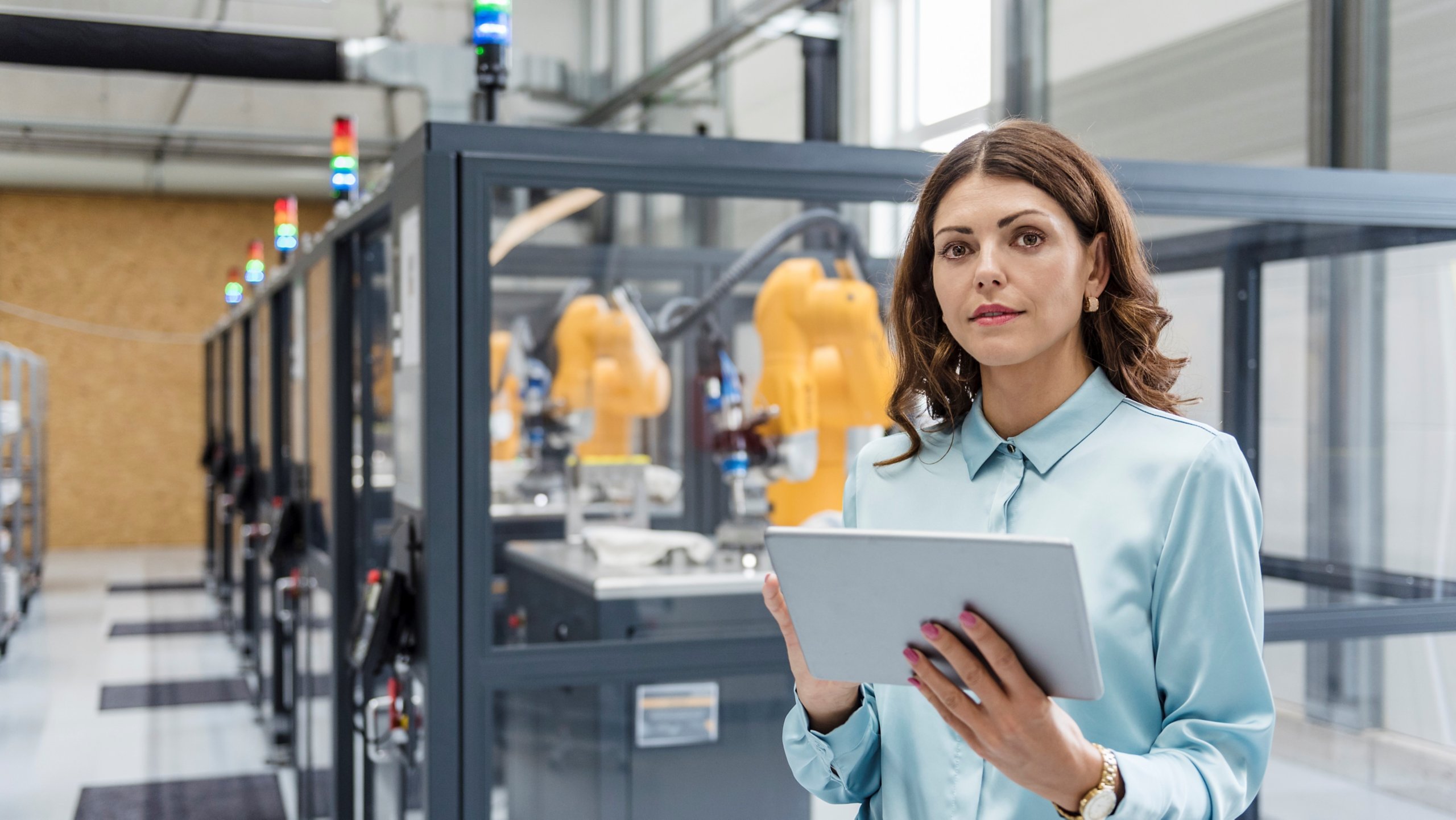 Mujer de negocios de pie junto a un equipo de fabricación mientras sostiene una tableta
