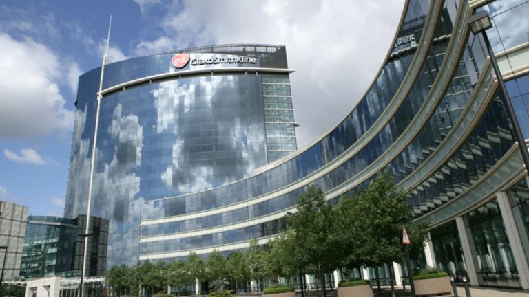 Des nuages blancs dans un ciel bleu se reflètent sur la façade du siège de GlaxoSmithKline au Royaume-Uni.