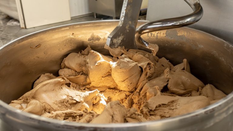 Making dough for bread in a kneader in a bakery. Industrial mixer for kneading dough. One of the stages of making bread dough