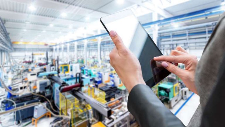 Una empleada ingresa datos en una tableta mientras observa una planta de fabricación