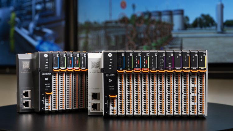 Front-facing view of two PointMax I/O systems (XT and non-XT variants) on a table, with industrial application images in the background