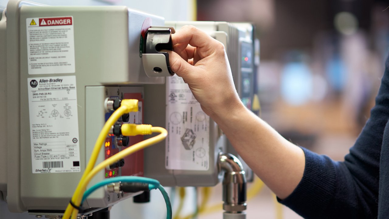 Weibliche Hand bedient einen Schalter in Herstellerumgebung