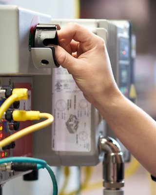 Female hand using a switch in a manufacturing environment