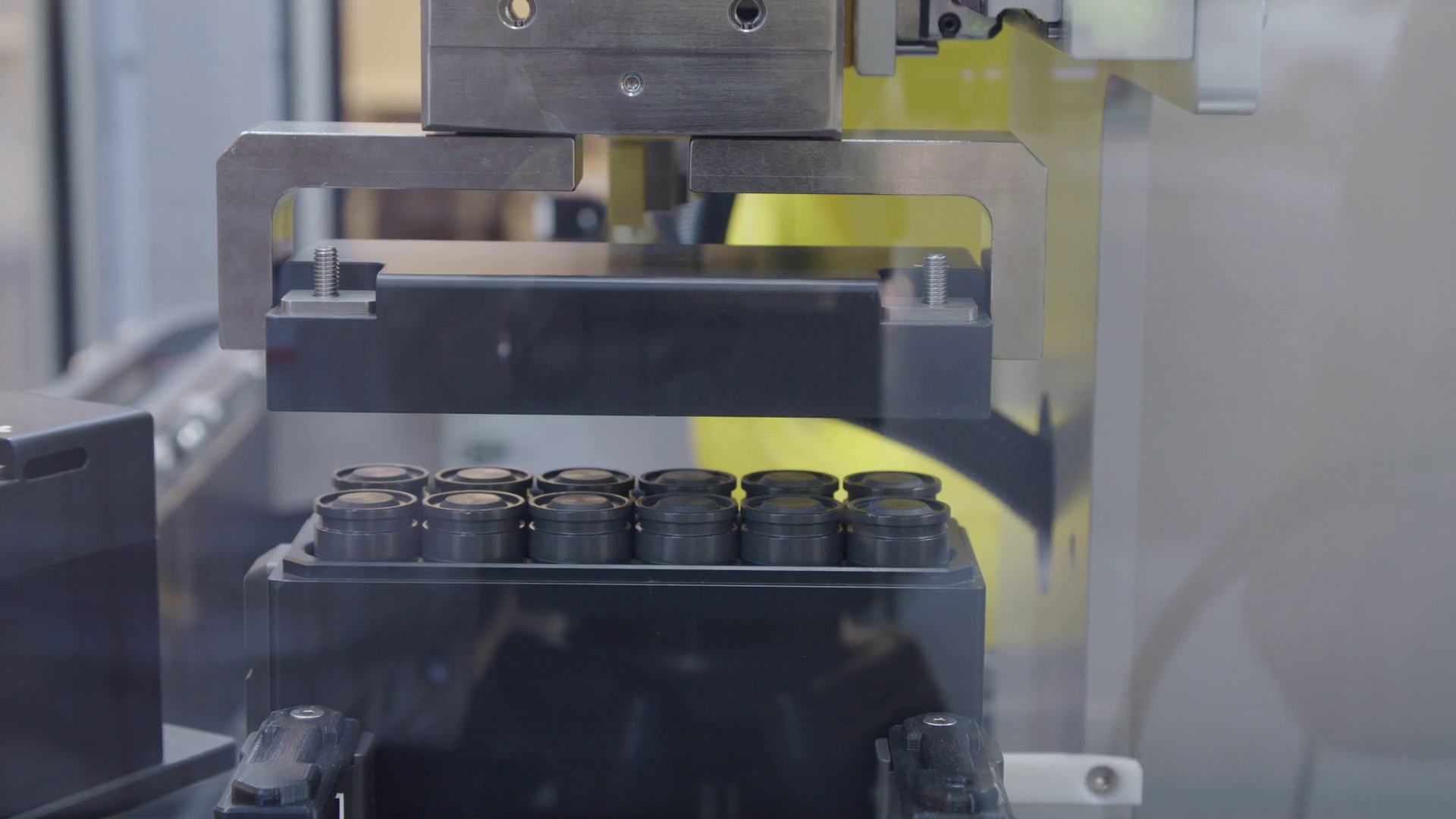 Battery being assembled on production line with a robotic arm placing cover