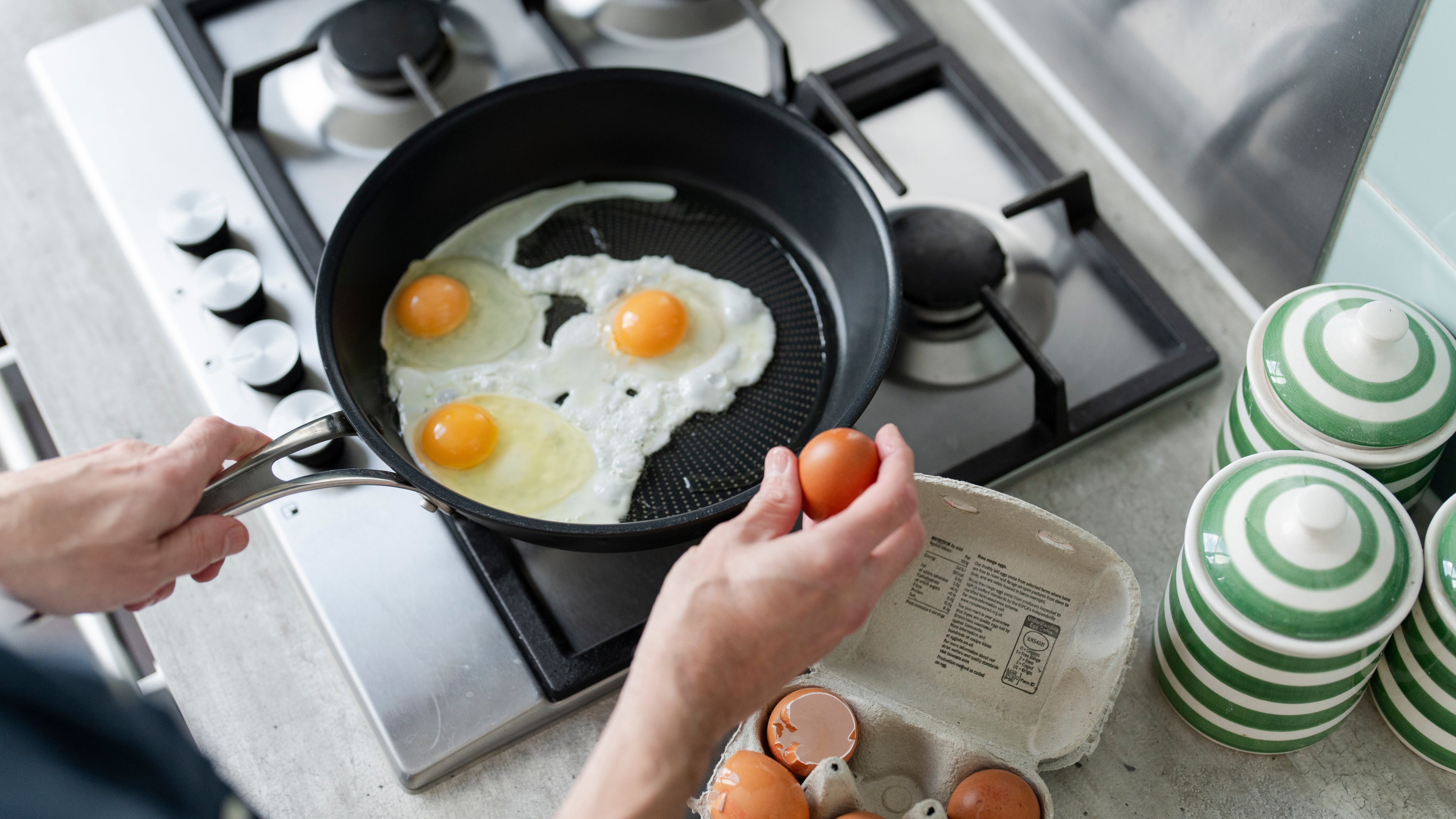 Close-up of person breaking egg into pan