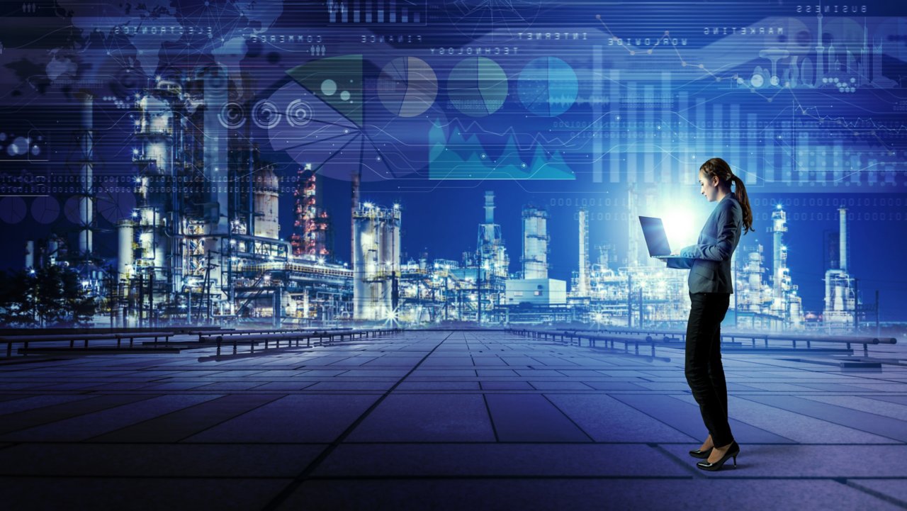 Vue numérique d’un établissement industriel extérieur avec une employée tenant un ordinateur portable qui communique avec tous les processus industriels
