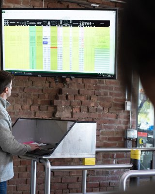 Rockwell Automation employee viewing FactoryTalk AssetCentre software on large monitor with coworker