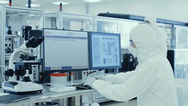 Pharmaceutical worker at monitors with Factory Talk PharmaSuite software running