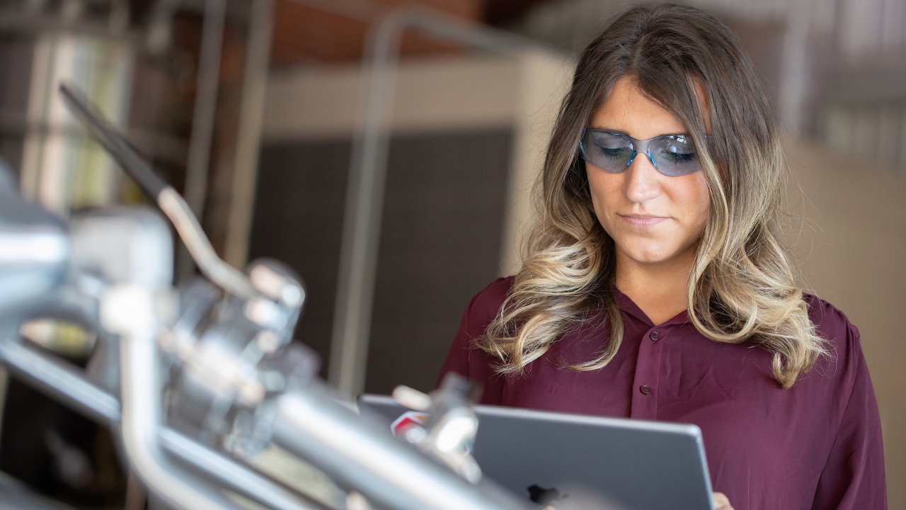 一名女性工程师正在生命科学工厂内使用其平板电脑上的 FactoryTalk PhamaSuite 制造执行系统查看数据