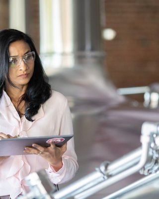 Female employee assesing the quality in a production area and entering the results into her tablet
