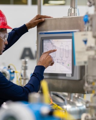 Employé de Rockwell Automation portant un casque rouge et saisissant des informations dans l’application logicielle FactoryTalk View via l’écran tactile d’un moniteur de l’usine