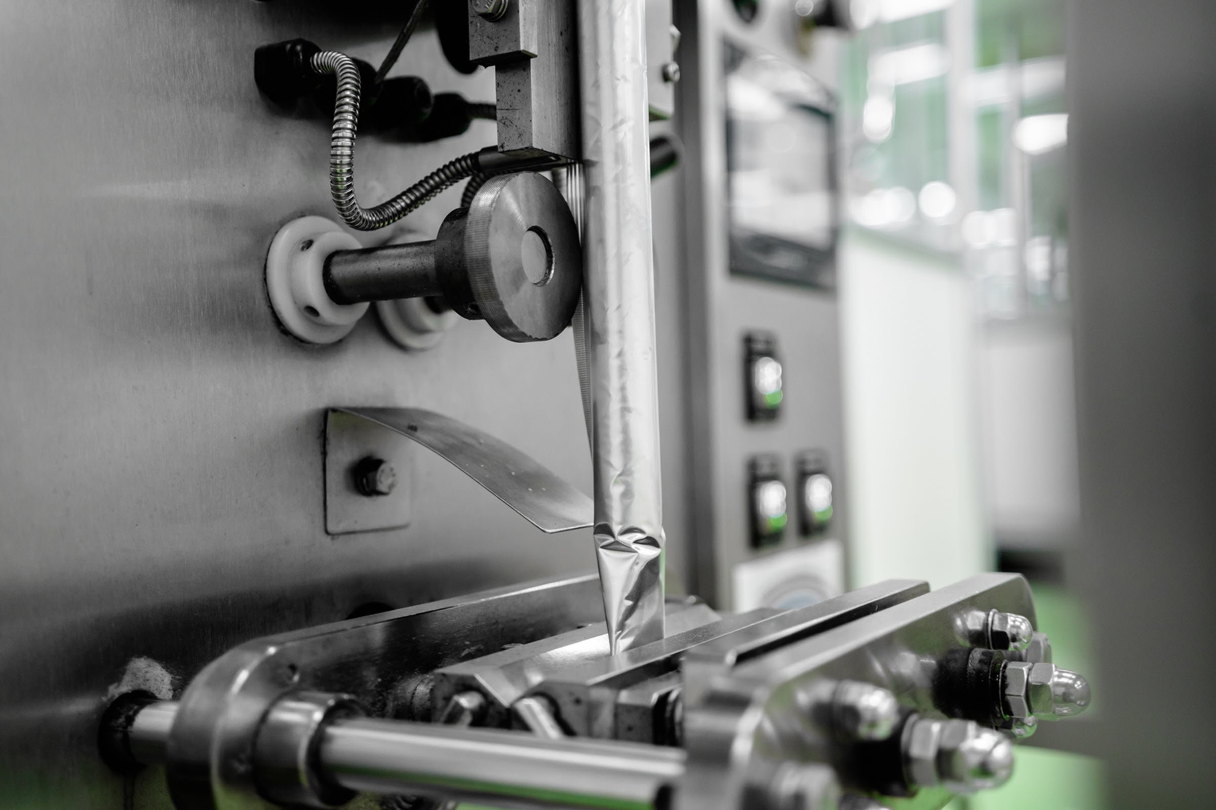 An industrial machine in a factory setting, surrounded by pipes and equipment.