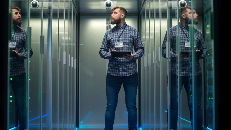 Portrait of adult bearded man and standing in server room in data center