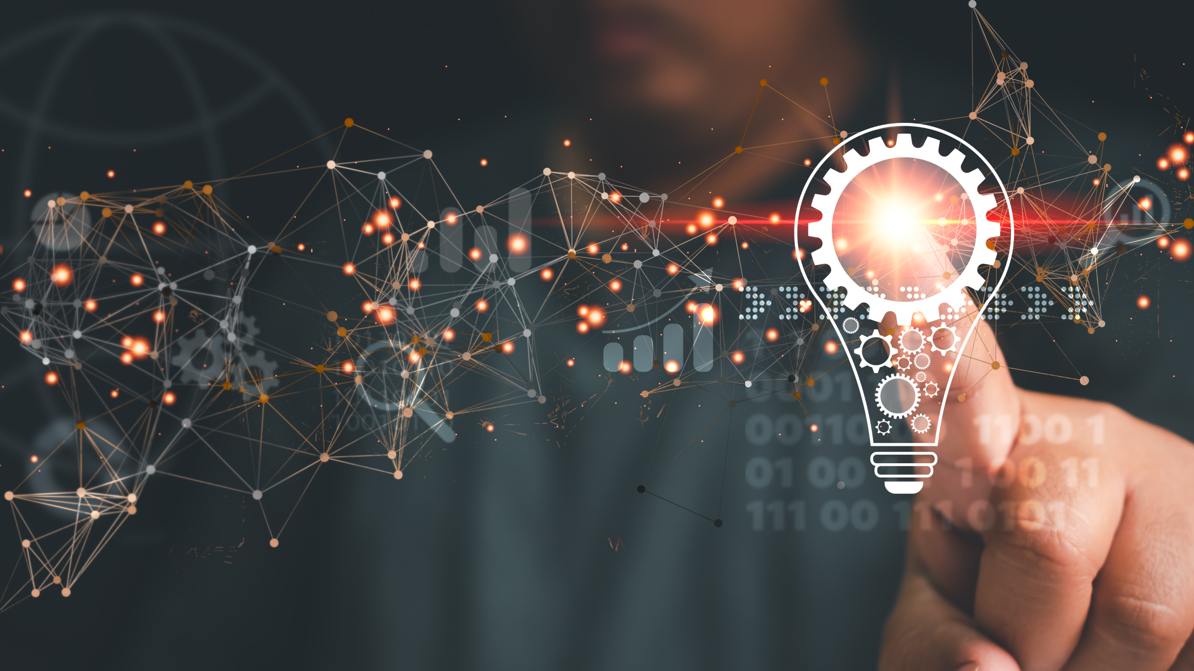 Close-up of a hand touching a glowing digital lightbulb icon connected to a network of nodes and data points, representing innovation, AI, and interconnected technology on a dark background with orange and blue highlights