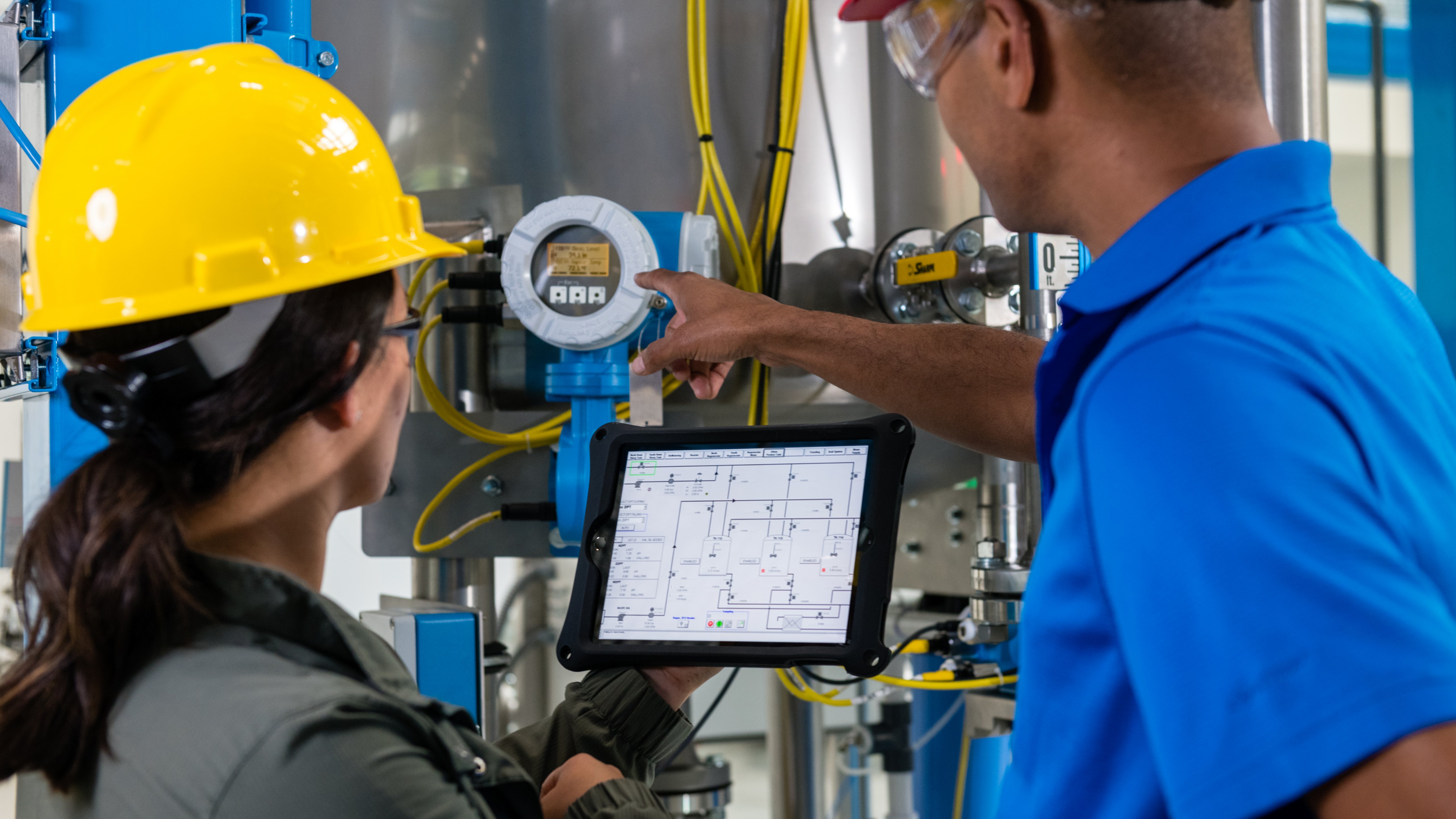 Male and female manufacturing employees viewing a gauge to troubleshoot production