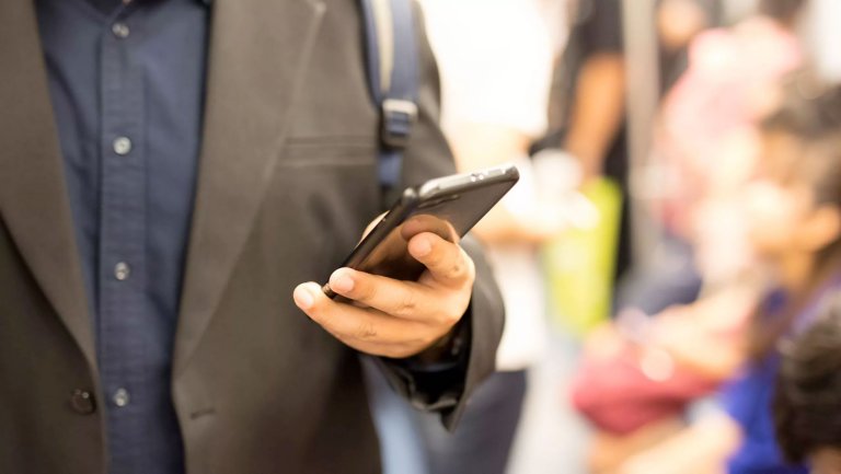 Homme portant un costume marron et tenant un téléphone portable