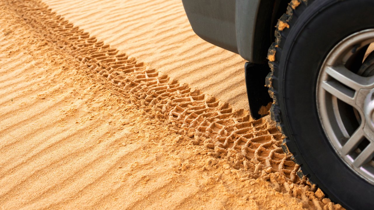 Primer plano de vehículo dejando huellas en la arena