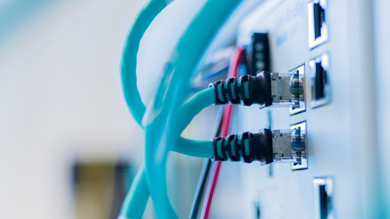 Dois cabos ethernet azuis conectados em uma parede em um data center industrial