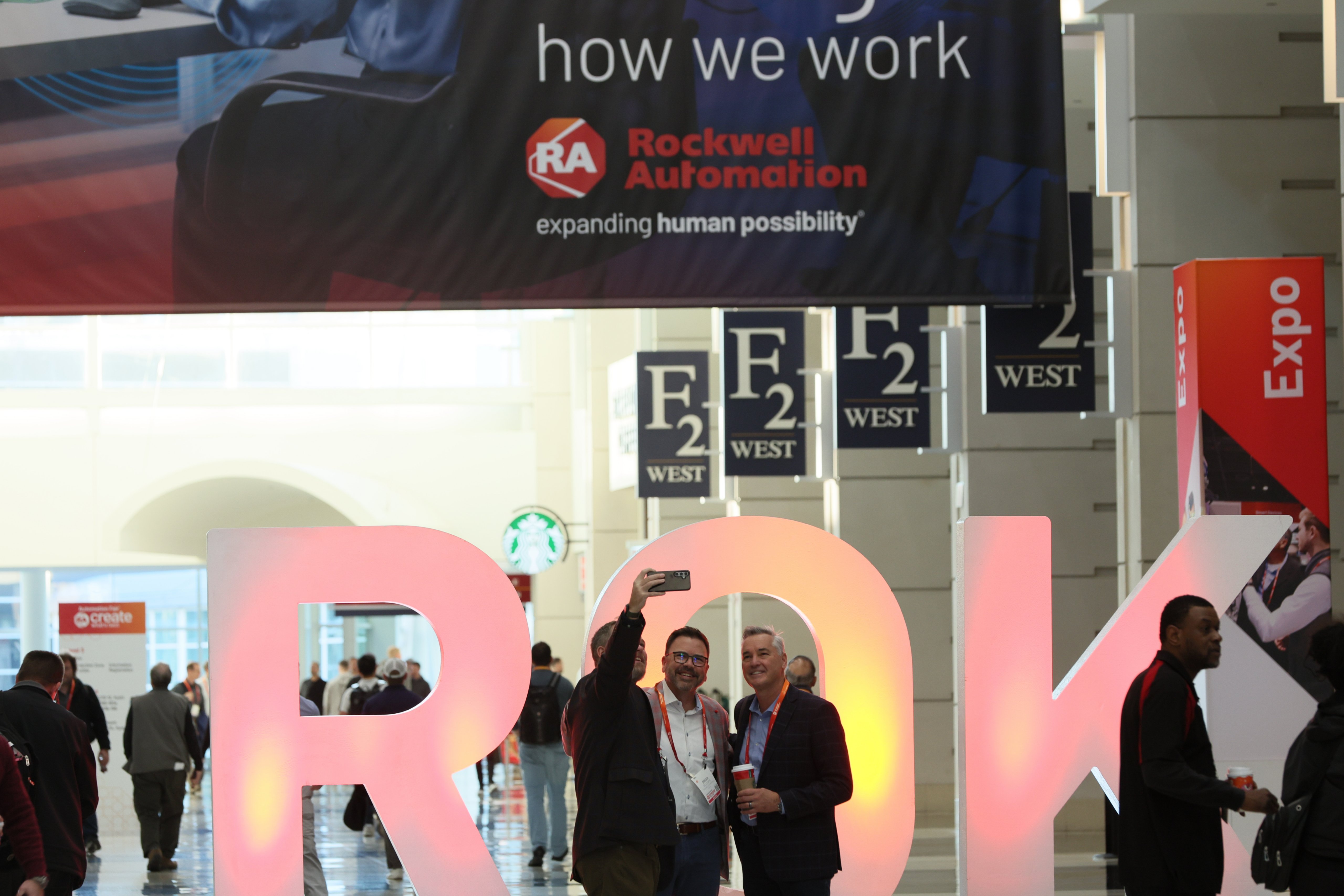 Three men taking a selfie in front of the ROK letter at Automation Fair
