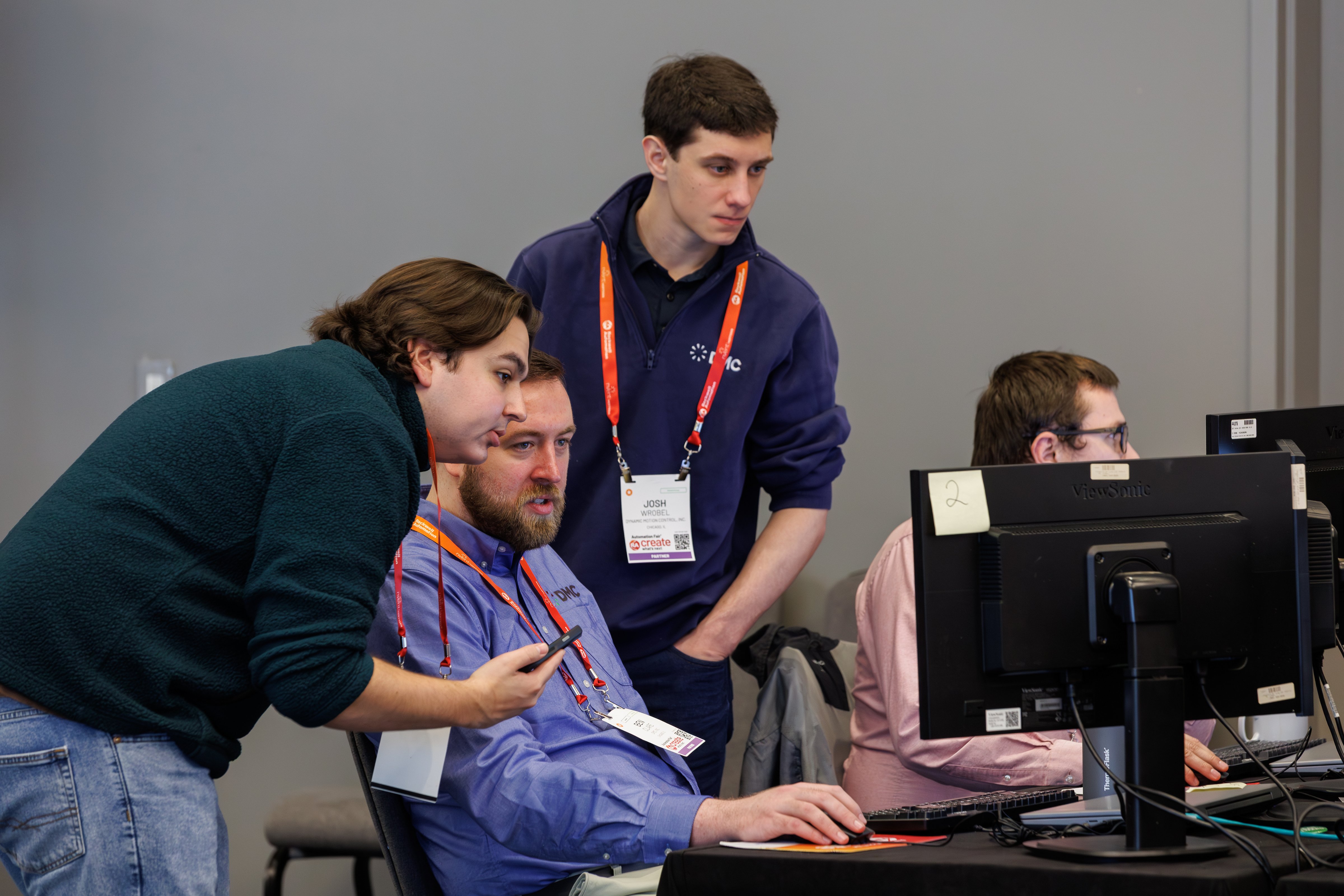 A group of people huddle around a computer