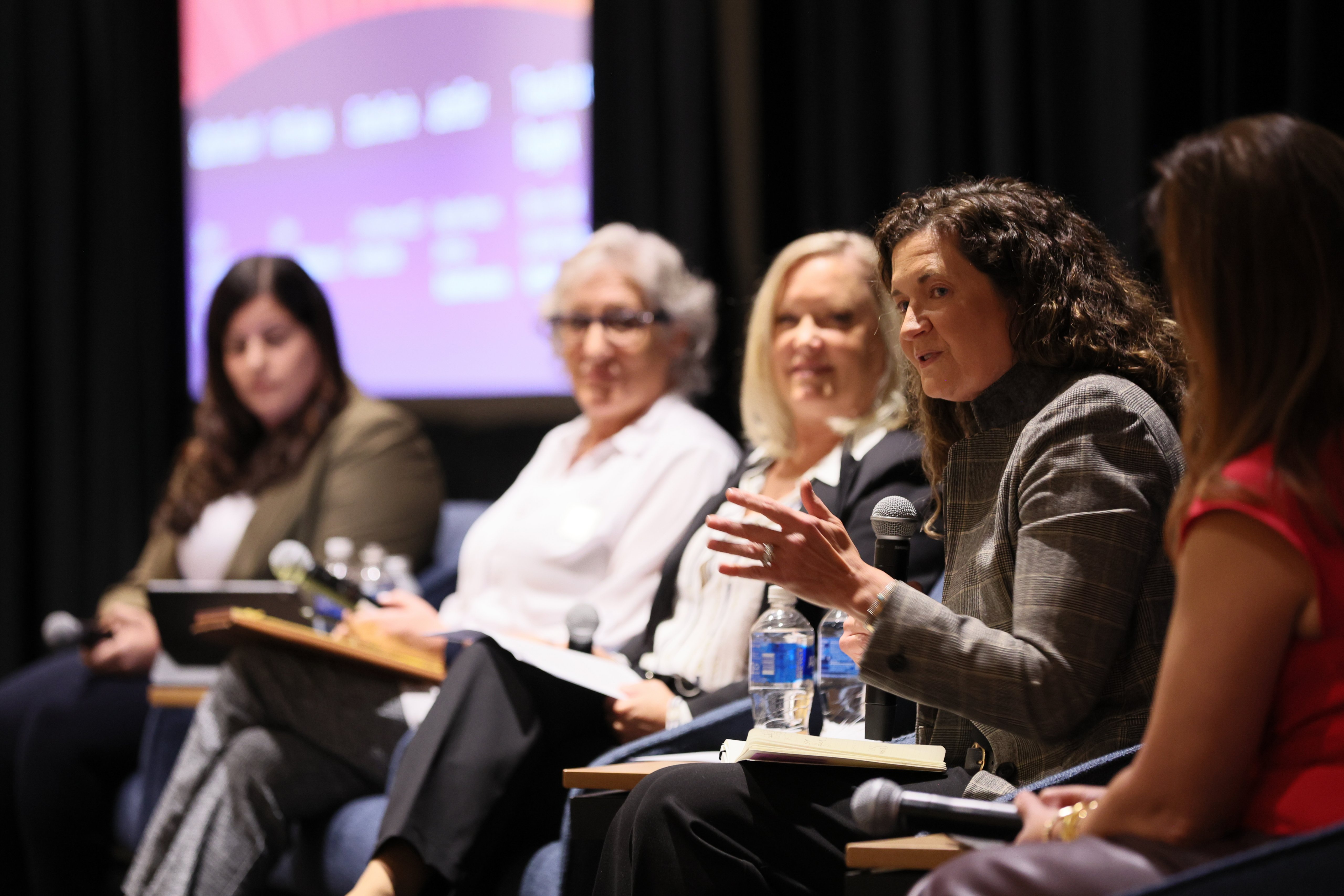Women speaking in a panel on a stage