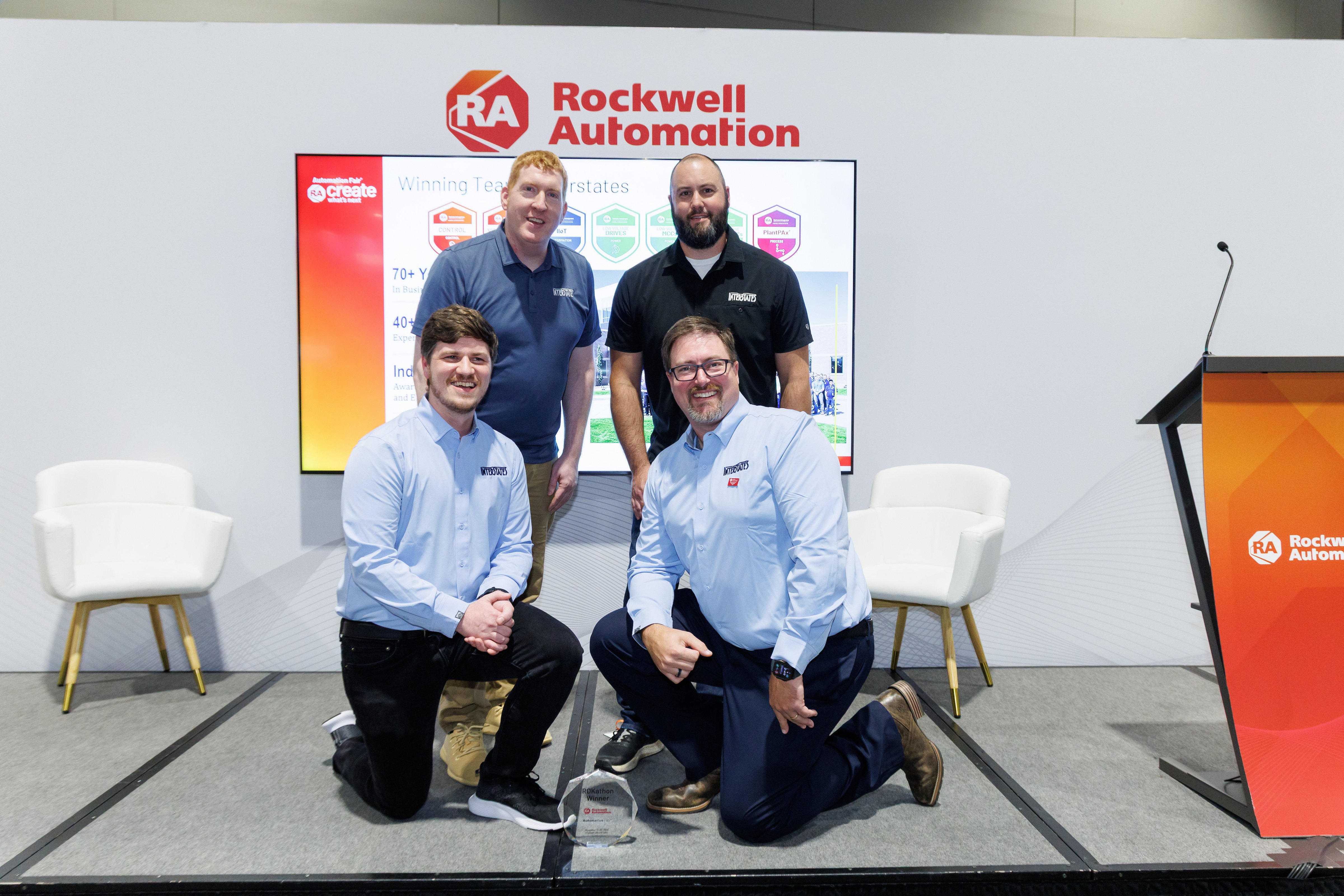 Four men pose on stage at the Automation Fair Discovery Theater