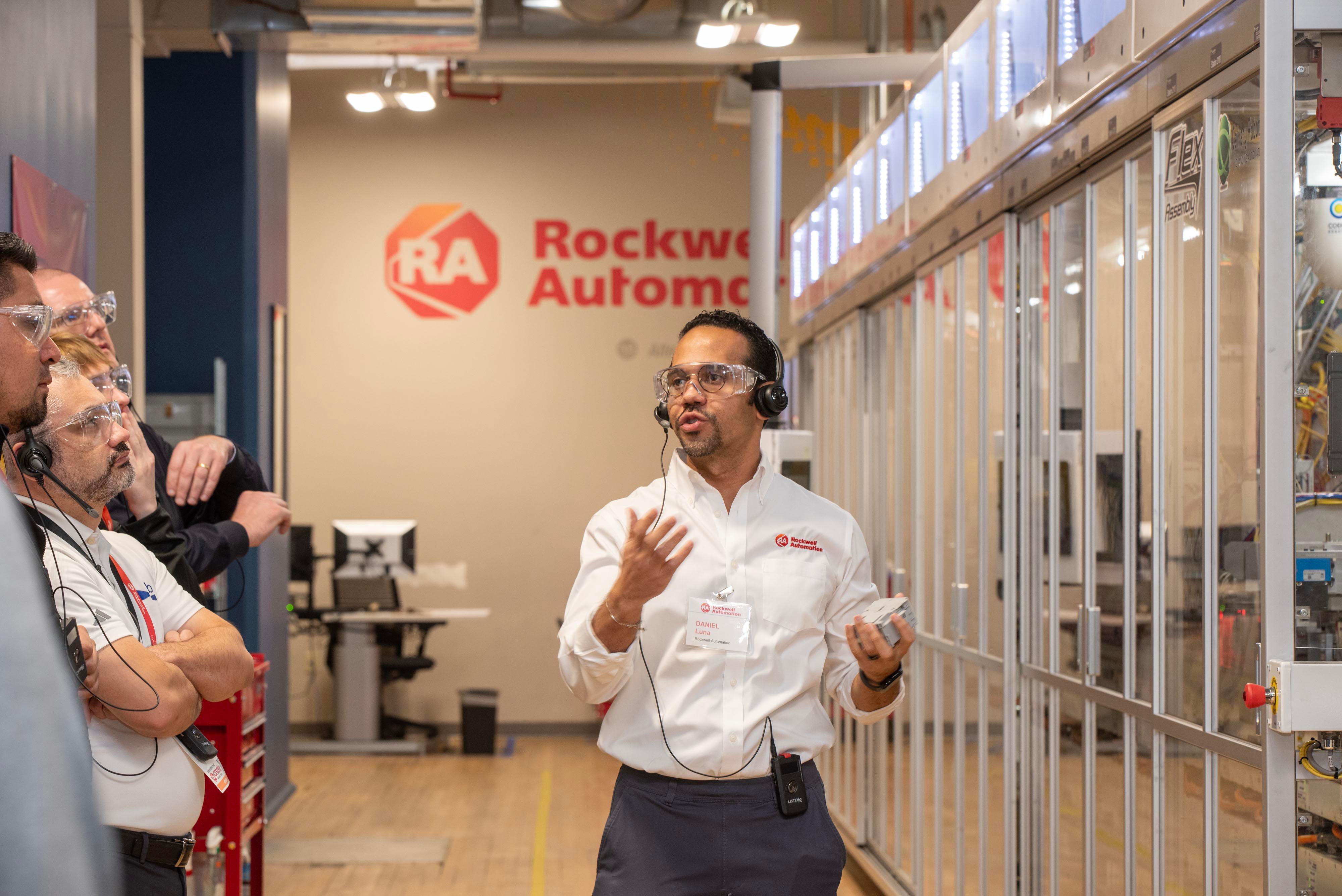 A man presents to a group of people in front of a machine at an Off-site Tour to Rockwell Automation Headquarters 