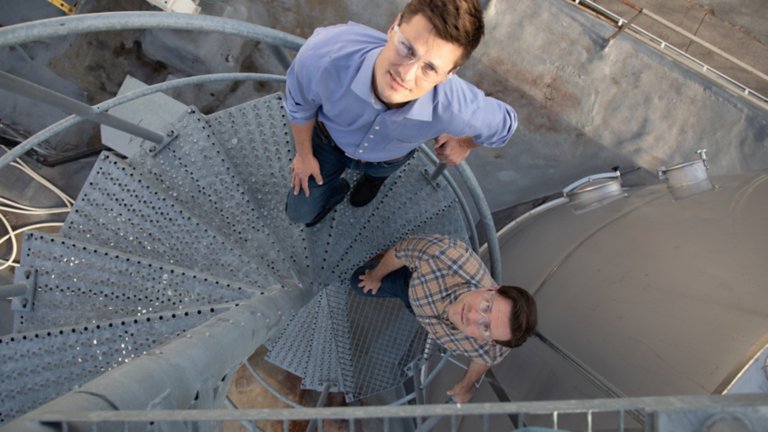 Aerial view of two males wearing safety glasses standing on a rounded metal staircase