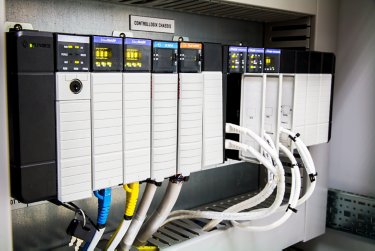 An electrical panel displaying multiple wires and switches, emphasizing the integration of a PLC for efficient operations.