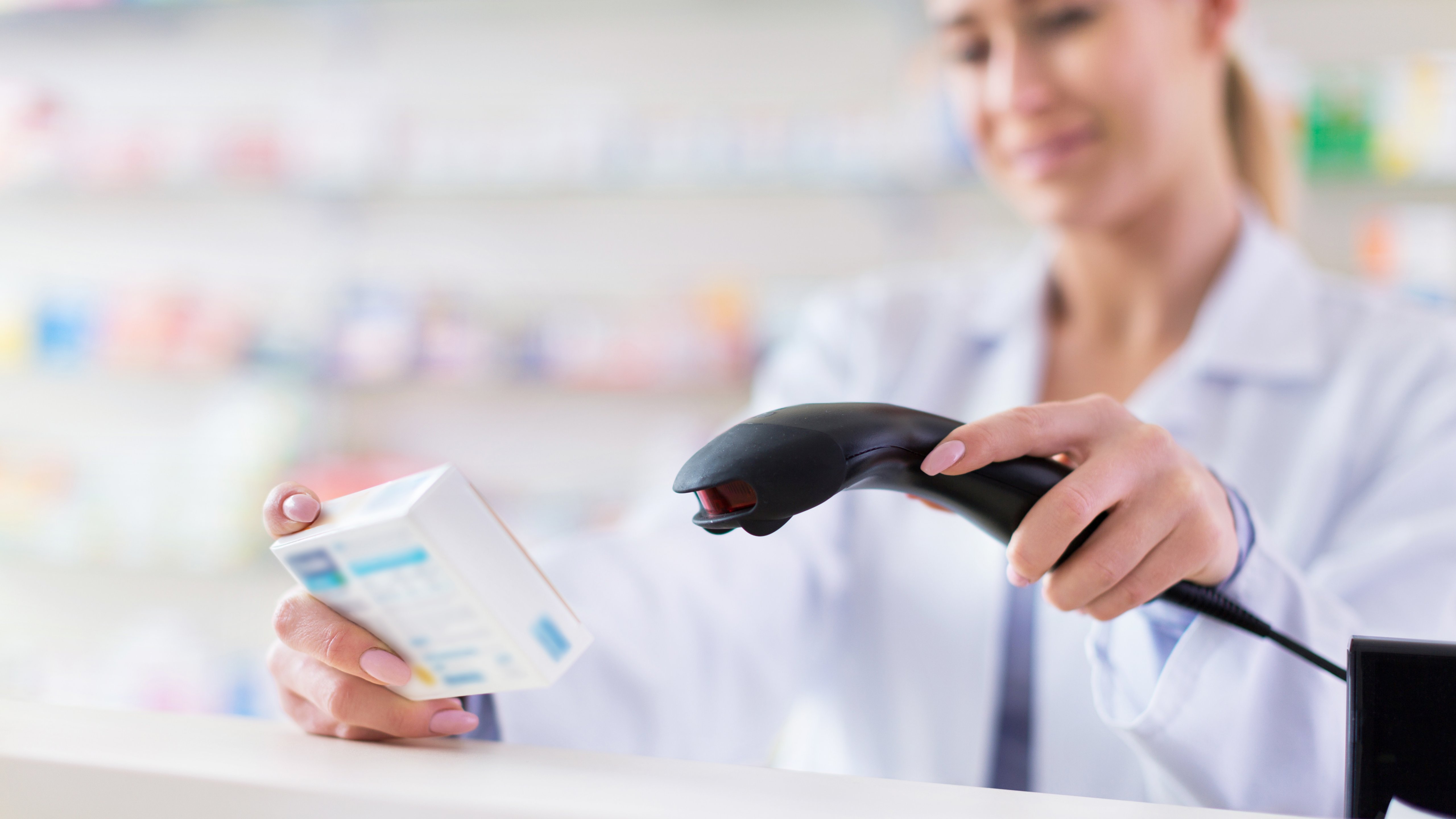A female life sciences professional scans a packaged product to track its movement through the manufacturing supply chain.