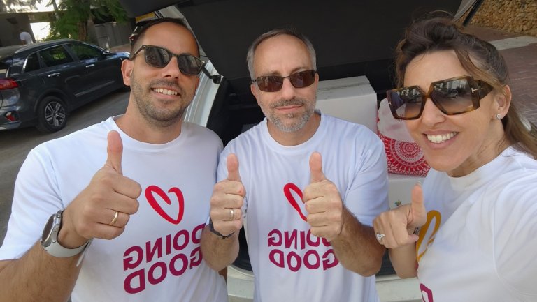 Three employees giving thumbs up to the camera wearing "Doing Good" shirts
