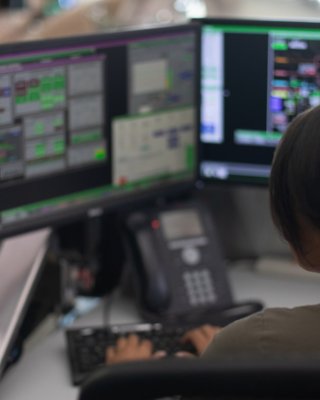 Une employée assise à son poste devant un écran affichant des informations saisit des données dans le programme du logiciel