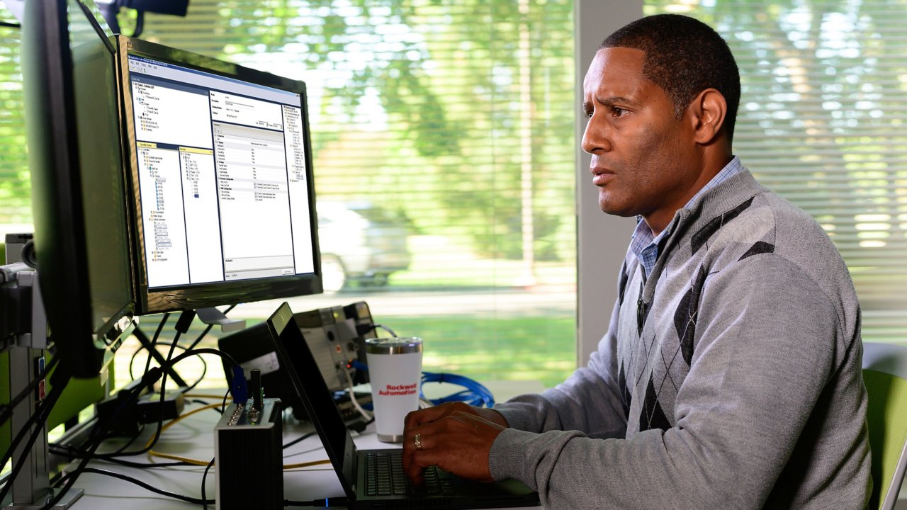 Un empleado de Rockwell Automation observando su monitor mientras añade información al software Studio 5000 Application Code Manager