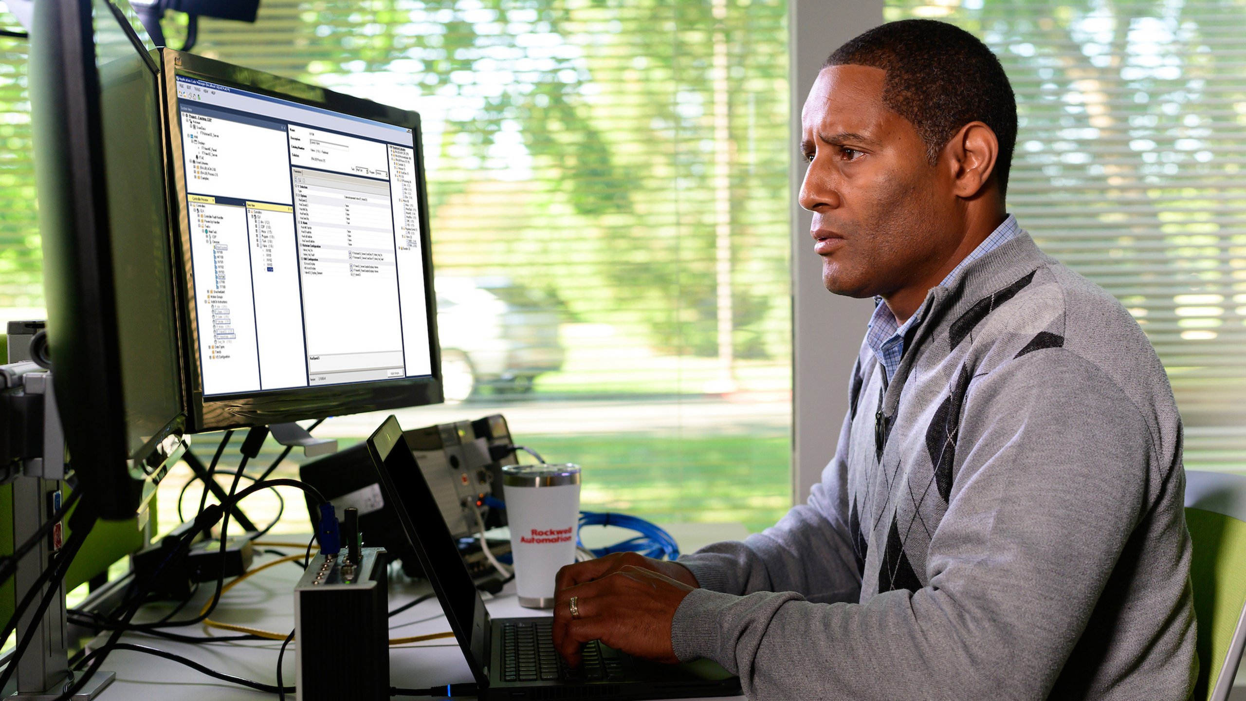 모니터를 보면서 Studio 5000 Application Code Manager 소프트웨어에 정보를 추가하는 Rockwell Automation 직원