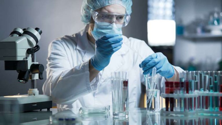 Técnico de laboratorio farmacéutico añadiendo gotas de un líquido en un tubo de ensayo