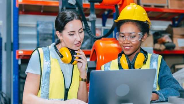 Women engineer worker working team training together at work in modern advanced robot welding machine factory.