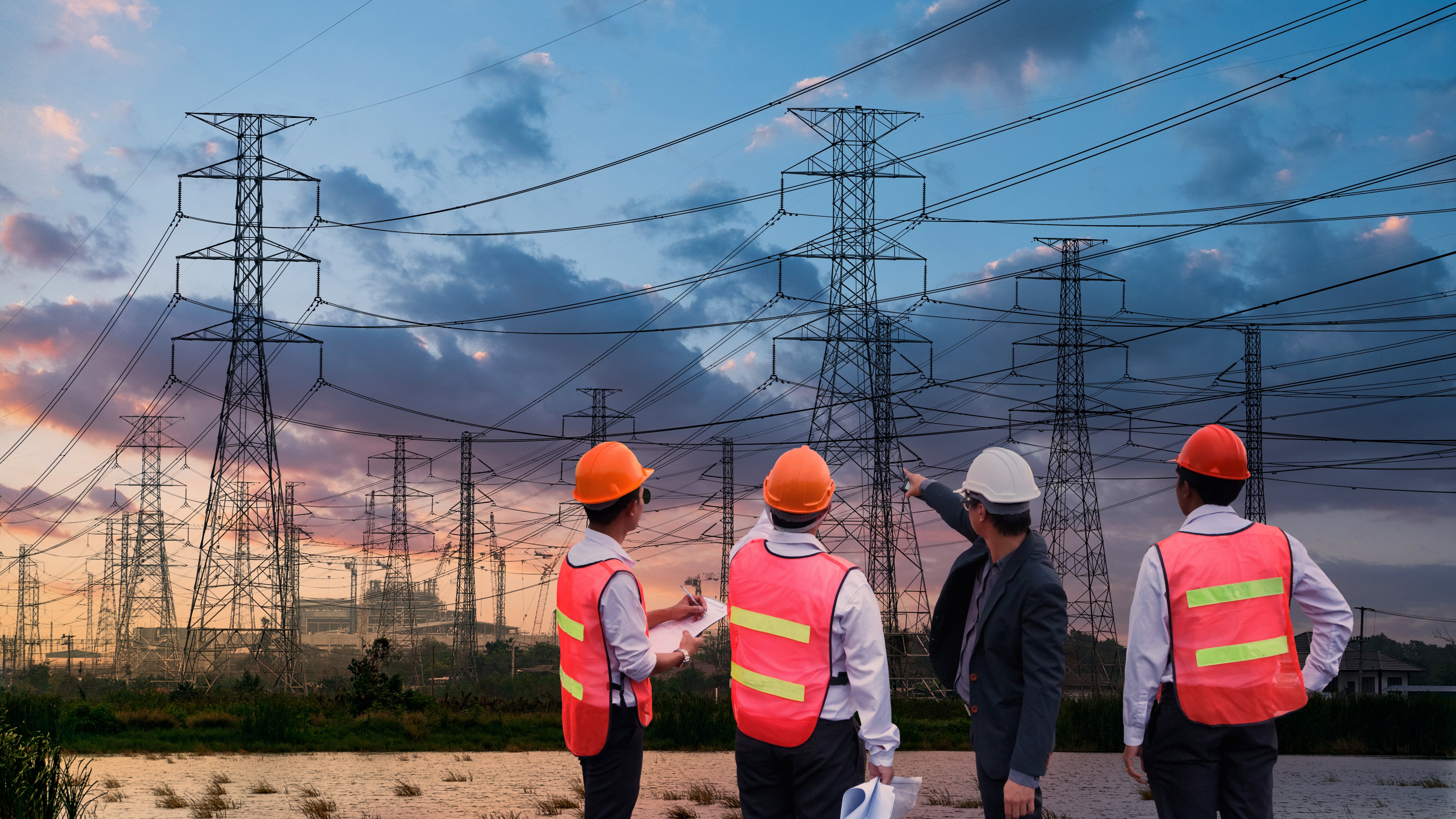 Silhouette high voltage electric tower and engineer team on sunset time and sky on sunset time background.