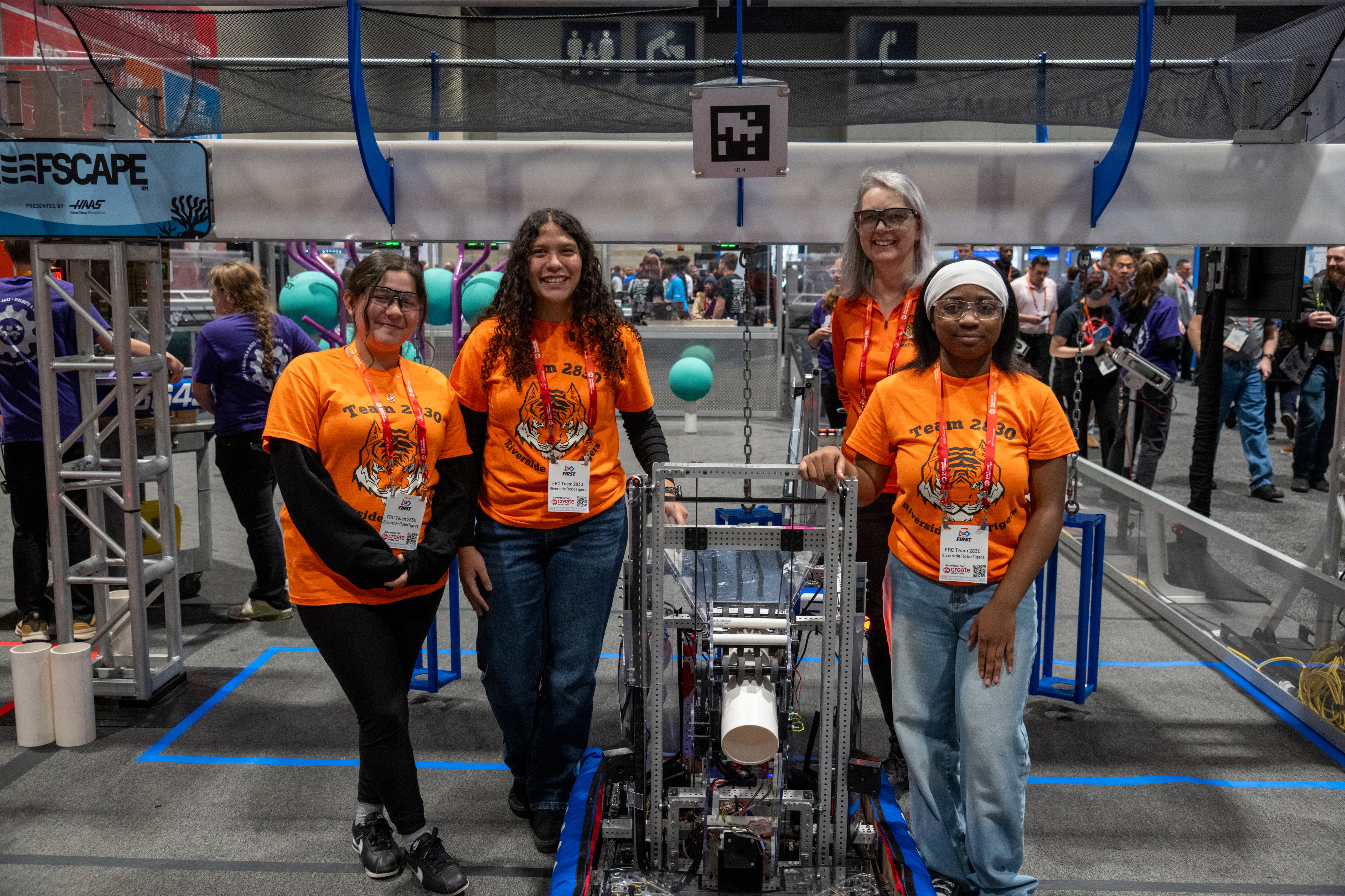 Three students and a teacher pose with their robot at the Automation Fair event