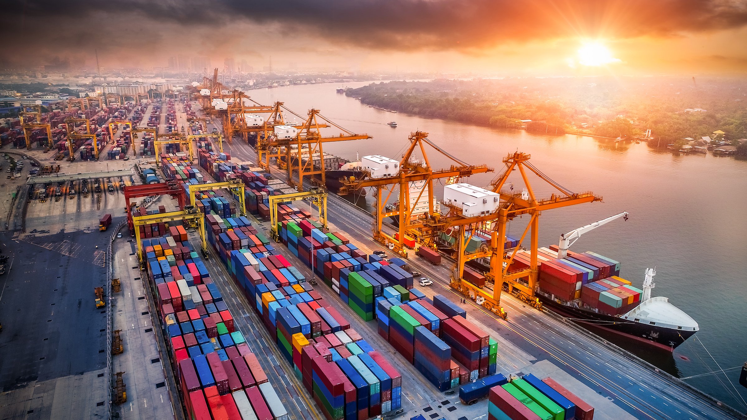 Ships loading at cargo container filled dock at sunset