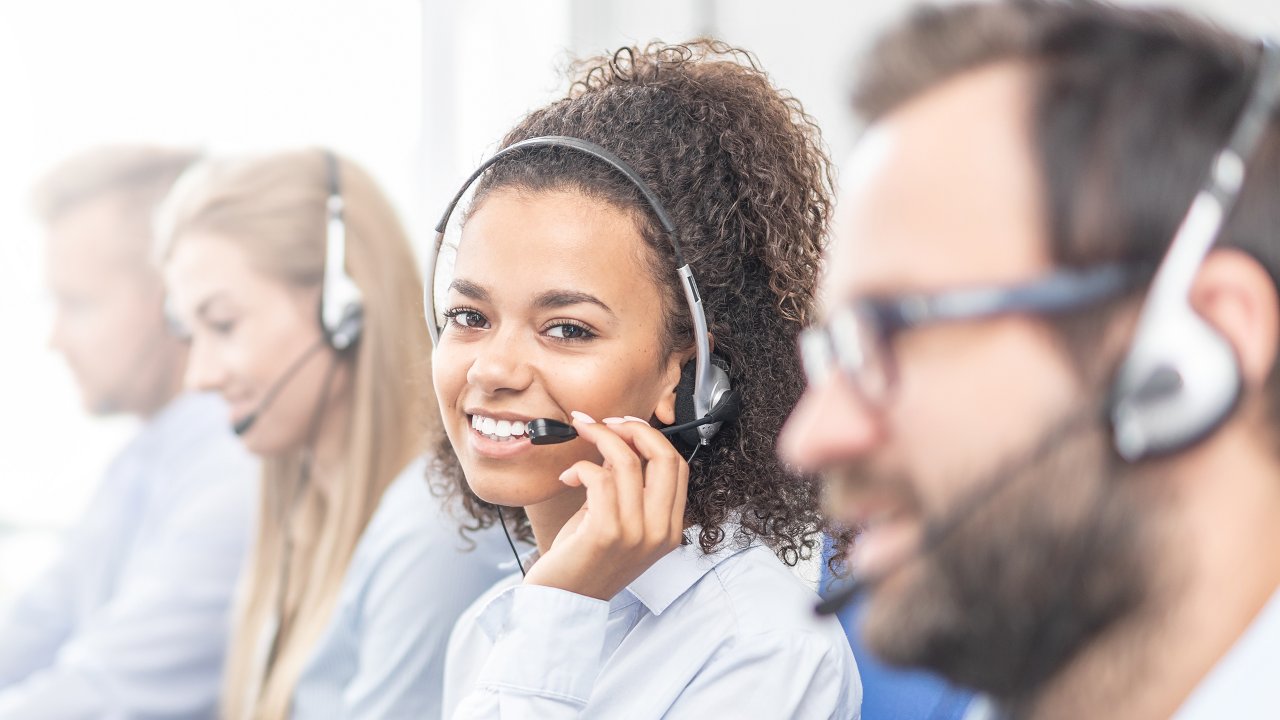 4 customer Service representatives sitting in call center wearing headsets