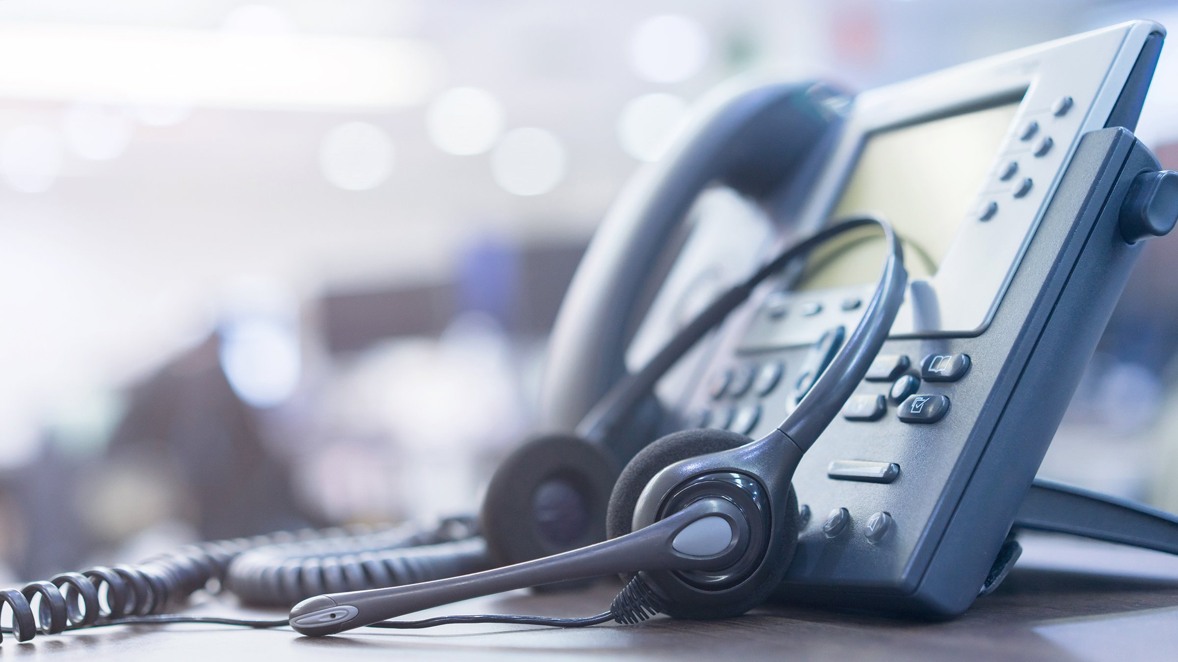 Headset leaning up against a call center phone