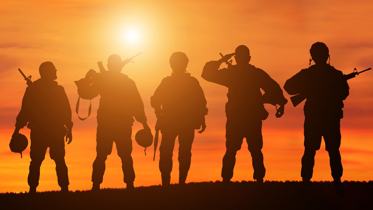silhouette of solider saluting against sunrise