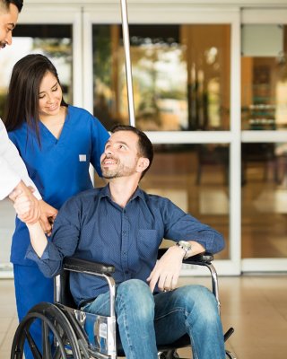 nurse holding wheelchair with patient shaking hands and speaking with doctor