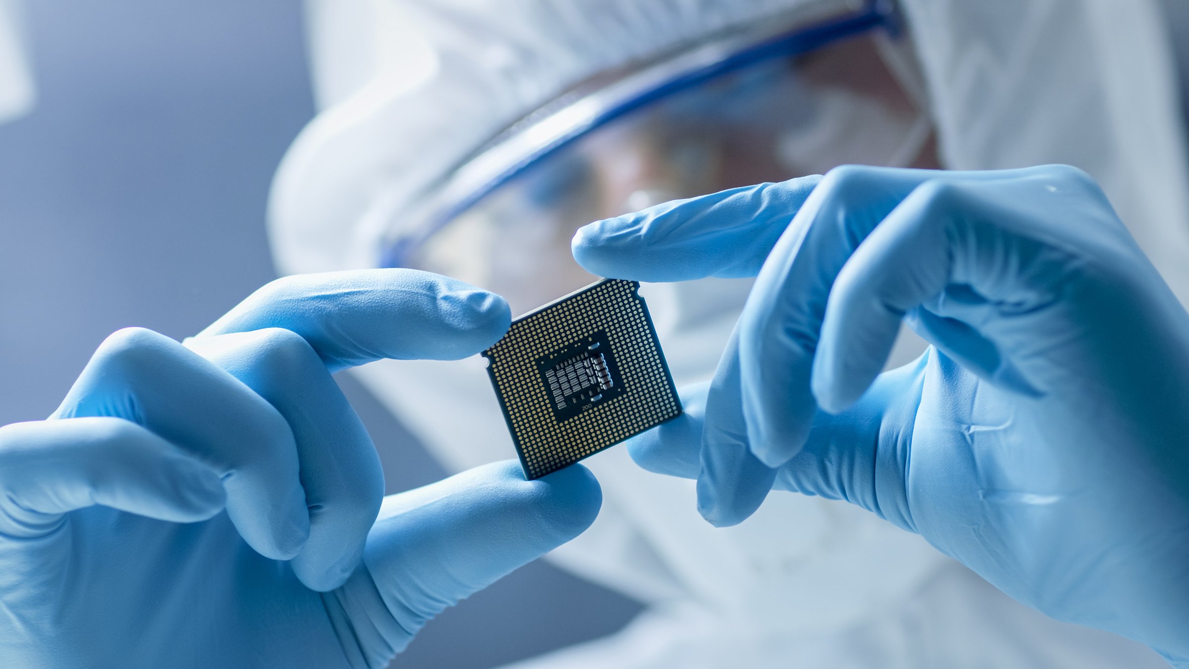 Person in clean suit examining microchip